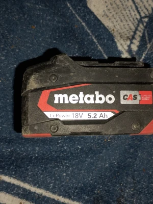 Metabo 18V 5.2Ah batteri - Säljer ett svart och rött Metabo Li-Power batteri med 18V och 5.2Ah kapacitet. Batteriet är av CAS-typ och har en robust plastkonstruktion. Perfekt för dig som behöver extra kraft till dina elverktyg. Märkt med tydlig Metabo-logga och teknisk info på sidan. Fungerar utmärkt. 