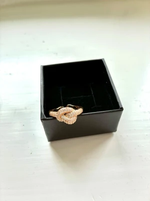 Justerbar ring med kristaller  - Reglerbar ring i stål med en knut av kristaller. Kristallerna är ingjutna och inte pålimmade, som på billigare smycken. Just nu passar ringen storlek 17, men kan både minskas och ökas i omfång med flera millimeter. Eftersom kristallerna inte går hela vägen runt så behöver man inte gå till guldsmed för att utöka omfånget.  Köpt på Walk in my closet medan de låg vid Östermalms saluhall för 1150kr. Knuten är 12x10 mm stor.  Kan skickas eller hämtas hos mig på Kungsholmstorg.