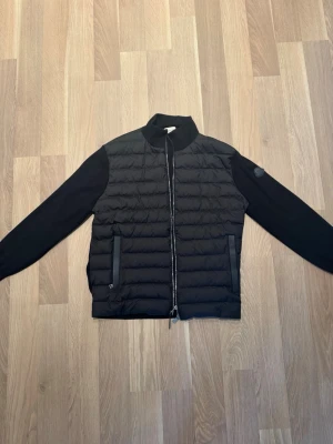 Moncler Cardigan Black label - Moncler cardigan black label med läderdetaljer på fickor och dragkedjan.