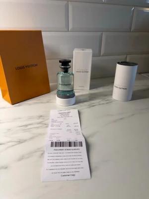 Louis Vuitton Imagination parfym - Lyxig parfym från Louis Vuitton, modellen Imagination. Flaskan är genomskinlig med svart lock och blågrön vätska. Kommer med originalförpackning, elegant orange låda och vit cylinderformad ask. Perfekt för dig som vill ha en exklusiv doft i snygg design.