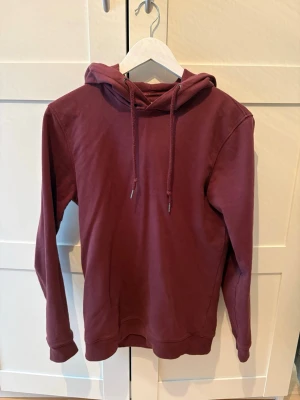 Vinröd Hoodie - En snygg vinröd hoodie som passar perfekt till dig som vill vara stilren nu på våren. Hoodien är rätt tunn och sitter bra på kroppen.