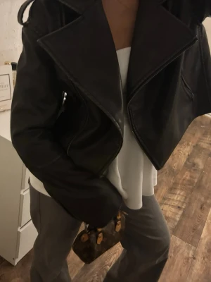 Grönsvart läder jacka - Snygg svart oversized skinnjacka med breda slag och dragkedja. Jackan har en cool, boxig passform och ger en edgy vibe till din outfit. Perfekt för dig som vill ha en trendig och stilren look. Passar till både jeans och byxor.