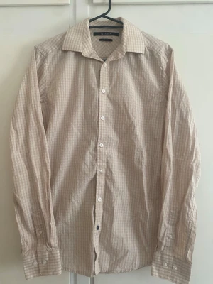 Beige rutig skjorta från Stenströms - Klassisk beige skjorta från Stenströms med diskret rutigt mönster. Skjortan har lång ärm, knappar framtill och klassisk krage. Tillverkad i mjuk bomull som känns skön mot huden. Perfekt för en clean och stilren look.