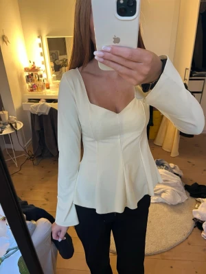 Ljusgul långärmad topp med v-ringning - Säljer en stilren ljusgul topp med lång ärm och v-ringad hals. Toppen har en figurnära passform upptill och faller ut i en lätt utsvängd nederdel. Perfekt för dig som gillar en feminin och elegant look. Från Gina tricot 14+ men passar mig som är en S!