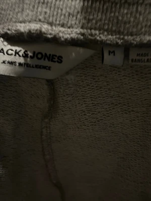Grå mjukisbyxor från Jack & Jones - Säljer ett par klassiska grå mjukisbyxor från Jack & Jones. Byxorna har resår i midjan och muddar vid bensluten för en skön passform. Perfekta för chill dagar hemma eller när du vill ha det bekvämt. Tillverkade i mjukt material.