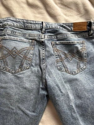 Ljusblå lågmidjade jeans Gina tricot  - Ljusblå lågmidjade jeans med klassisk femficksmodell och snygga kontrastsömmar på bakfickorna från Gina tricot. Jeansen har normal midja och raka ben i storlek 44 (L/XL). Materialet är denim i bomull med en lätt tvättad look. Endast används fåtal gånger. 