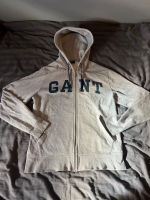 Grå zip hoodie från GANT - Snygg grå hoodie från GANT i storlek L. Säljer då den inte används. Mitt pris 399kr hör av dig vid någon fråga! Inga defekter!