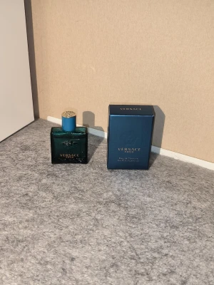 Versace Eros Eau de Toilette 5 ml - Versace Eros Eau de Toilette med en elegant blå glasflaska och matchande blå kartong. Flaskan har guldfärgad detalj på korken och klassisk Versace-logga. Perfekt för dig som gillar exklusiva och fräscha dofter men vill inte betala för stort pris!