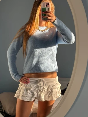 Ljusblå stickad tröja - Säljer en ljusblå stickad tröja med rund hals och långa ärmar. Tröjan har en enkel och klassisk design med ribbstickade muddar vid ärmslut och nederkant. Perfekt att matcha med jeans eller kjol för en chill look. Sååå fin färg 