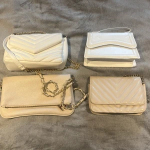 Fyra beige och vita axelväskor - Säljer fyra snygga axelväskor i beige och vitt, alla med guldfärgade kedjeremmar. Går att köpa en om man vill det, eller allihopa. Priset som står är för alla 4. Pris går alltid att diskutera