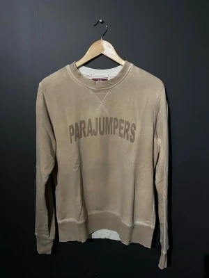 Beige sweatshirt från Parajumpers - Snygg beige sweatshirt från Parajumpers med rund halsringning och ribbade muddar. Stor logga framtill i matchande ton. Perfekt för en avslappnad och stilren look. Tillverkad i mjukt material för extra komfort.