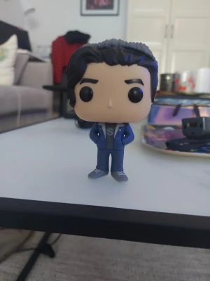 Blå Funko Pop! figur - Säljer en Funko Pop! vinylfigur med svart hår, blå jacka och blå byxor. Figuren har stora svarta ögon och står med händerna i fickorna. Perfekt för samlare eller som dekoration.