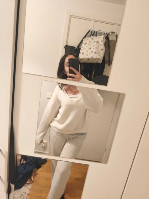 Mysig vit loungewear-set - Säljer ett supermysigt loungewear-set i vitt. Setet består av en långärmad tröja med v-ringning och matchande byxor med resår i midjan. Perfekt för chill dagar hemma. Materialet ser ut att vara mjukt och stretchigt, troligen bomull eller bomullsblandning.