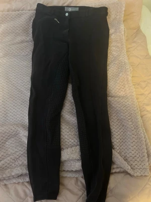 Svarta ridbyxor från Horze - Säljer ett par svarta ridbyxor från Horze med helskoning i silikon för extra grepp. Byxorna har en dragkedjeficka fram,. Snygg och sportig modell som passar perfekt till ridning och träning. Storlek 164/170, pris kan diskuteras! 