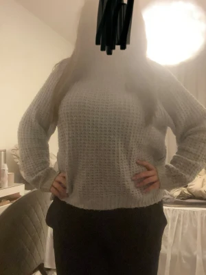 Ljusgrå stickad tröja - Mysig ljusgrå stickad tröja med avslappnad passform och rund hals. Tröjan har ett diskret rutmönster i stickningen och långa ärmar med breda muddar. Perfekt för lager på lager och enkel att matcha till olika outfits. Liten fläck på brösten men är inte tydlig. Pytte lite smink vid kragen 