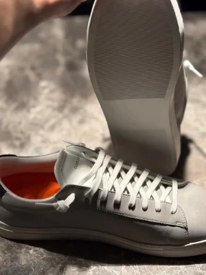 Oliver cabell, ALDRIG ANVÄNDA!  - Snygga grå sneakers från oliver Cabell med vita snören och en diskret logga på sidan. Skorna har en låg profil, vit sula och orange innersula som ger en cool kontrast. Tillverkade i slätt läder med detaljer i mocka och textil.    ALDRIG ANVÄNDA . FÖLJER MED EN DÄMPNINGSSULA FÖR drygt $50
