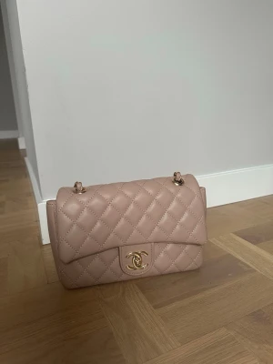Beige/rosa Chanel handväska - Säljer en beige/rosa handväska från Chanel med klassiskt mönster och guldfärgad kedja. Väskan har den ikoniska CC-låset framtill och axelrem i kedja och läder. Pris kan diskuteras 