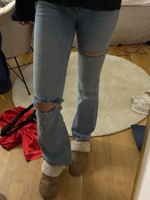 Ljusblå slitna jeans med hål - Säljer ett par ljusblå bootcut jeans med slitningar och hål vid knäna. Storlek S💞