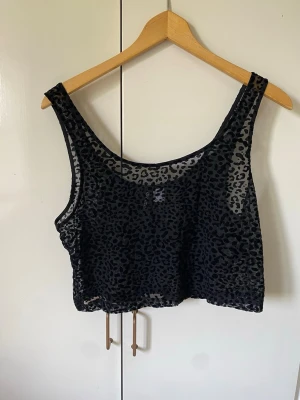 Svart leopardmönstrad mesh linnetopp - Säljer en  svart linnetopp med transparent mesh och flockat leopardmönster.  Står storlek 40 men beror  på hur man vill den ska sitta och hur stor byst man har, så mer som storlek 38 tycker jag🤍