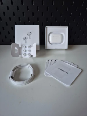 Apple AirPods pro gen 2 - Säljer ett par vita Apple AirPods Pro med laddningsetui, extra silikontoppar och laddningskabel. Hörlurarna är in-ear och har en stilren, minimalistisk design i blank plast. Perfekta för dig som vill ha trådlöst ljud och smidig anslutning till Apple-enheter. Garantin giltigt till 17 maj, perfekt för dig som vill ha ett par stabila lurar men inte vill betala en förmögenhet 