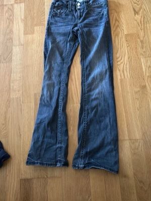 Blå bootcut jeans med dubbla knappar från gina tricot  - Snygga gråa bootcut jeans med dubbla knappar i midjan från gina tricot. 