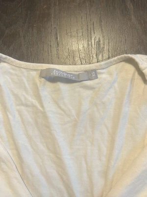 Vit långärmad topp från InWear - Snygg vit långärmad topp från InWear med twistad detalj framtill. Tillverkad i mjuk bomull som specialfeature. Perfekt för dig som gillar enkel men stilren design och vill ha något som funkar till många 'fits.