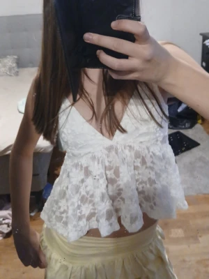 Vit spetsig sommar topp - Söt vit croppad linnetopp med spetsdetaljer och volang nedtill. Djup v-ringning och tunna axelband ger en luftig och somrig känsla. Jätte fin till sommaren