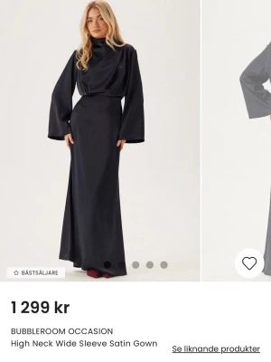 Marinblå långklänning i satin från Bubbleroom - Elegant marinblå långklänning i satin med hög krage och vida ärmar. Klänningen har en slät och glansig yta som ger ett lyxigt intryck. Perfekt för dig som vill ha en stilren och sofistikerad look. Oanvänd prislapp på.