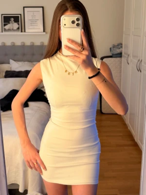 Vit kortklänning - Säljer en stilren vit kortklänning med ärmlös design och hög hals. Min dröm klänning men har tyvärr blivit för liten för mig..😢