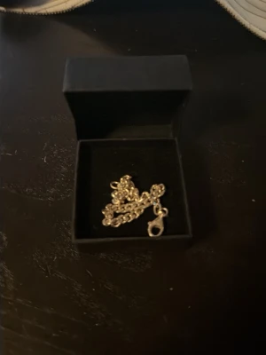 Silver kedja från Gudhuset.se - Säljer en stilren silverfärgat armband i äkta silver från Gudhuset.se. Kedjan kommer i en svart ask med guldfärgad logga och har ett klassiskt lås. Perfekt accessoar för att lyfta din stil.