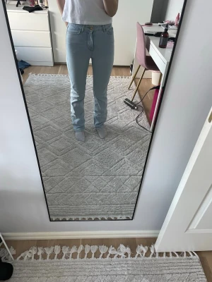 Ljusblå raka jeans med hög midja - Säljer ett par ljusblå jeans med rak passform och hög midja. Jeansen har klassisk femficksdesign och stängs med knapp och dragkedja. Perfekta till en avslappnad och trendig stil. Materialet är denim i bomull.