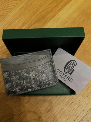 G@yard cardholder - Snyggt och exklusivt kortfodral från G i grått och svart med det klassiska G-mönstret. Tillverkat i läder med flera kortfack och elegant logotyp framtill. Perfekt för dig som vill ha en stilren och lyxig accessoar i fickan.