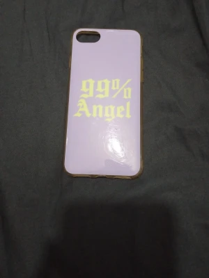 Lila mobilskal med text 99% Angel till iphone 8 - Snyggt mobilskal i lila med gul texten '99% Angel' på baksidan. Skalets kanter är transparenta och det är gjort i plast. Passar till mobil med en kameraöppning i hörnet. Perfekt för dig som vill ha en personlig touch på mobilen.