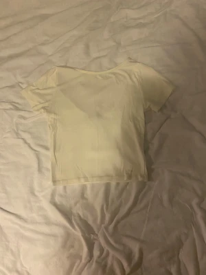 Vit croppad topp - En enkel och fräsch vit croppad topp med korta ärmar. Man kan ha den åt båda hållen, antingen som u-ringad eller med öppen rygg, lite smått nopprig.