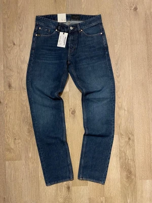 Mörkblå raka jeans från tiger of sweden - Snygga mörkblå jeans från tiger of sweden med en liten rak passform men endå lite slim så slim/straight och klassisk femficksdesign. Jeansen har en stilren look med diskreta detaljer och är tillverkade i kraftig denim. Perfekta för en clean och tidlös stil.