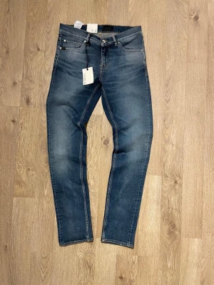 Blå slim fit jeans från tiger of sweden - Snygga blå slim fit jeans från tiger of sweden  med klassisk femficksdesign och lätt tvättade detaljer. Jeansen har normal midja, dragkedjegylf och är gjorda i mjuk bomullsdenim med lite stretch för extra komfort.