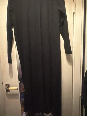 Svart långärmad LIBERTE   t-shirtklänning ALMA  - Svart långärmad t-shirtklänning från ALMA i storlek M/L. Klänningen har enkel och rak form med rund hals och är tillverkad i ett mjukt material som passar perfekt för en avslappnad look. Stilren och minimalistisk design. Är aldrig använd. Fick den i en Molly and My påse men inte min still så säljer den. 