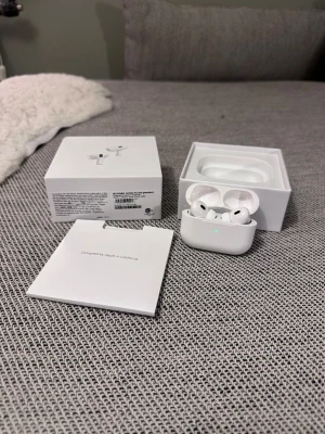 Apple AirPods Pro med laddningsetui - Säljer ett par Apple AirPods Pro i vitt med trådlöst laddningsetui. Hörlurarna har en stilren och kompakt design, levereras med originalförpackning, laddningskabel och extra öronproppar. Perfekta för dig som vill ha grymt ljud och smidig anslutning till din iPhone.