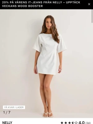 Vit kortklänning från Nelly - Stilren vit kortklänning från Nelly med vida korta ärmar. Klänningen har en enkel, minimalistisk design med rund halsringning och lätt struktur i tyget. Perfekt för en fräsch och modern look.