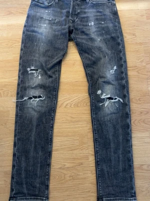 Jack & Jones jeans - Säljer ett par svarta slim fit jeans med slitningar. Jeansen har fem fickor, dragkedjegylf och en tvättad look med distressed detaljer. Perfekta för en edgy och avslappnad stil. Modellen är Jack & Jones Glenn/smil fit, strl w32l34