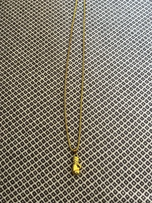 Guldigt halsband med boxhandske - Snyggt halsband i guldfärgad metall med en detaljrik boxhandske som hänge. Kedjan är tunn och glänsande, och hänget har coola snörningsdetaljer. Perfekt accessoar för dig som gillar sportiga smycken eller vill sticka ut med något unikt.