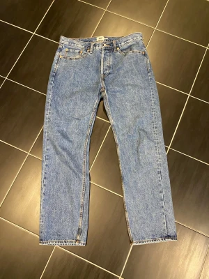 Blå raka jeans lager 157 - Klassiska blå jeans från Lager 157 i rak modell med fem fickor och gylf med knapp. Jeansen har en tidlös tvätt och är tillverkade i slitstark denim. Perfekta för en avslappnad och trendig stil. I använt men fint skick! Strl 33/32