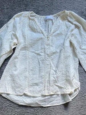 Vit blus från Zara - Säljer en vit blus från Zara med strukturerat tyg och dekorativa knappar framtill.
