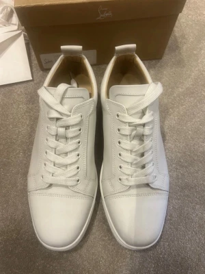 Christian Louboutin sneakers strl 41 (41-42) - Stilrena helvita sneakers från Christian Louboutin i slätt läder. Klassisk låg modell med vita skosnören och diskret design. Perfekta för dig som gillar minimalistisk och clean stil. Snygga detaljer och bekväm passform. De har gått igenom äkthetsverifiering och certifikat från de tillkommer vid köp. Samt box och alla tillbehör. Hör av er vid frågor och funderingar!