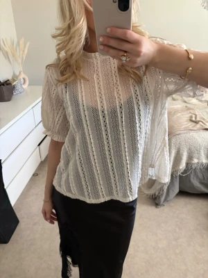 Vit spetsblus med puffärm - Säljer en vit, transparent spetsblus med fina lodräta mönster och puffiga korta ärmar. Blusen har rund halsringning och ett luftigt, romantiskt uttryck. Perfekt att styla med ett linne under för en trendig look.
