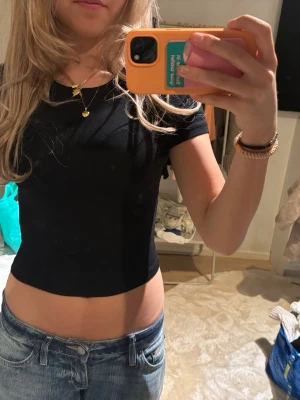 Svart croppad t-shirt - En svart, croppad t-shirt med rund halsringning och korta ärmar. Enkel och stilren modell som passar perfekt till jeans eller kjol. T-shirten har en tight passform och är tillverkad i ett mjukt material.