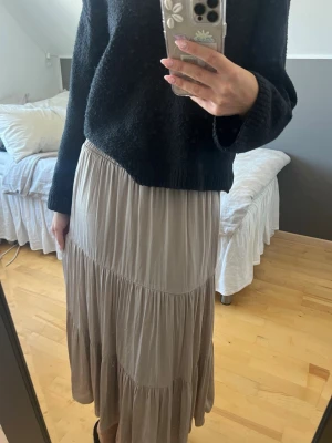 Beige långkjol - Säljer denna superfina beiga kjolen med volangdetaljer från Ginatricot. Den har väldigt mjukt och luftigt material med dubbelt tyg där innertyget är lite likt silke. Perfekt till sommaren!!☺️💕 