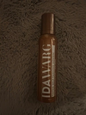 Ida Warg brun utan sol mousse - Brun utan sol mousse från Ida Warg i en brun plastflaska med vit text. Produkten är en tinted self-tanning mousse som ger en solkysst look. Perfekt för dig som vill ha en jämn och naturlig färg utan sol.