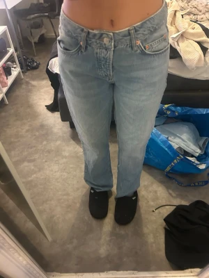 jusblå raka jeans - Säljer ett par klassiska ljusblå jeans  med rak passform och hög midja. Jeansen har fem fickor, knappgylf och är tillverkade i ett robust denimtyg. Perfekta för en avslappnad och trendig look.