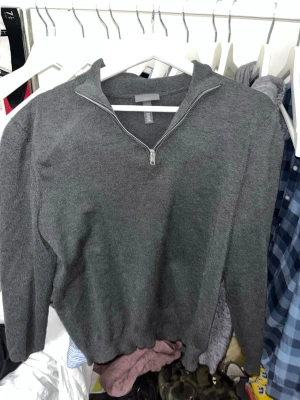 Grå stickad halvzip från H&M - Snygg grå stickad tröja från H&M i slim fit-modell med halvzip och ståkrage. Perfekt för lager-på-lager och enkel att matcha med jeans eller chinos. Ribbstickade muddar vid ärmslut och nederkant ger en clean look.